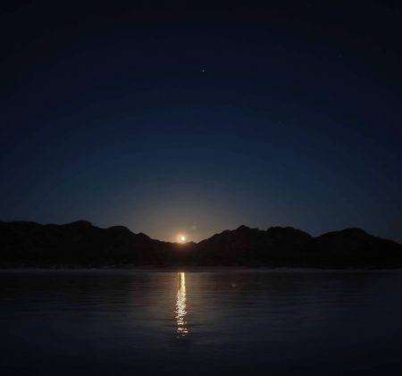 A full moon rising over the hills